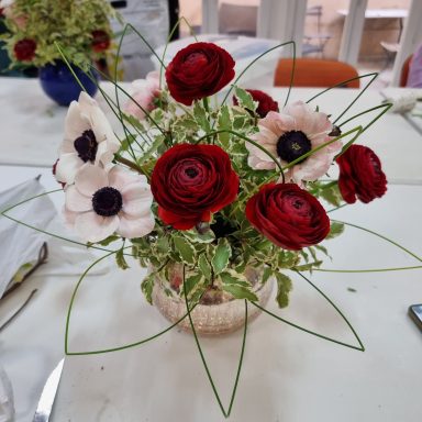 Bouquet de fleurs composé de roses rouges et anémones blanches.