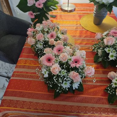 Arrangement de fleurs roses et blanches sur une nappe orange, avec une table décorée.