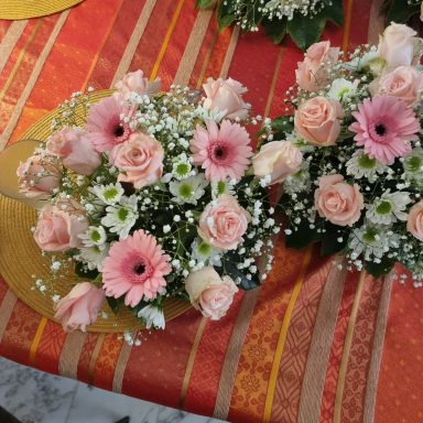 Bouquets de roses roses et gerberas sur une nappe colorée.