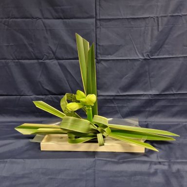Arrangement floral avec des feuilles vertes et des fleurs sur une base en bois.